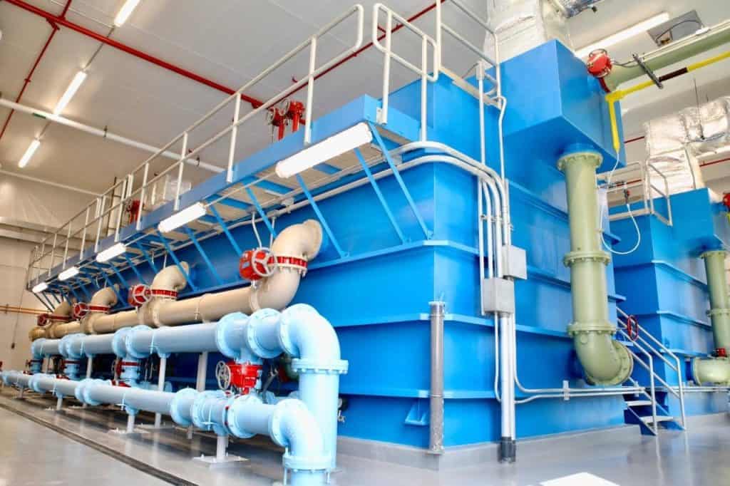 Industrial water treatment facility with large blue tanks and piping.