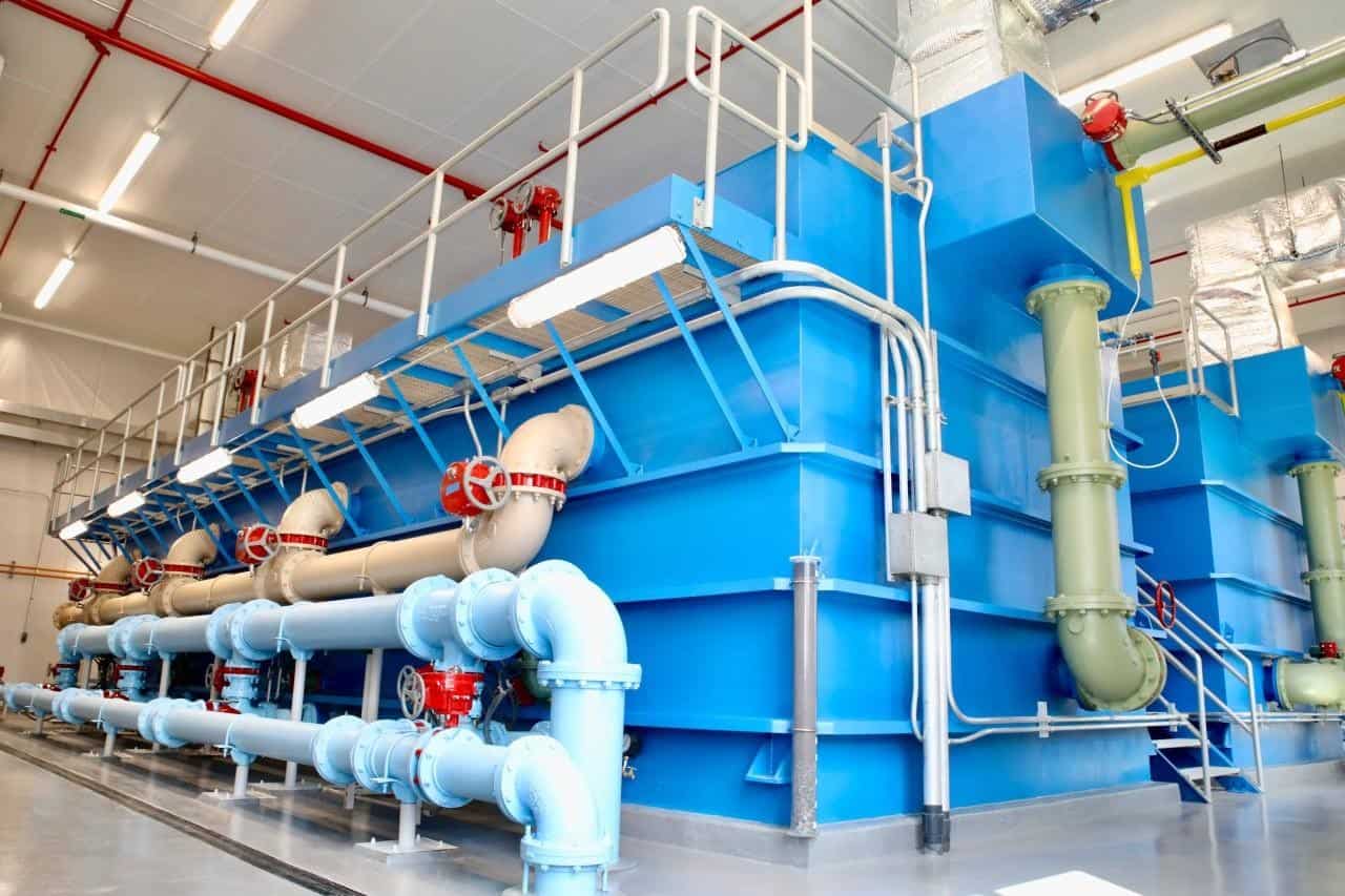 Industrial water treatment facility with large blue tanks and piping.